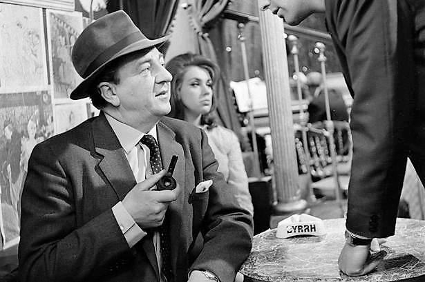 British-actor-Rupert-Davies-pictured-sitting-at-a-restaurant-table-in-a-scene-from-the-television-series-Maigret-in-1963